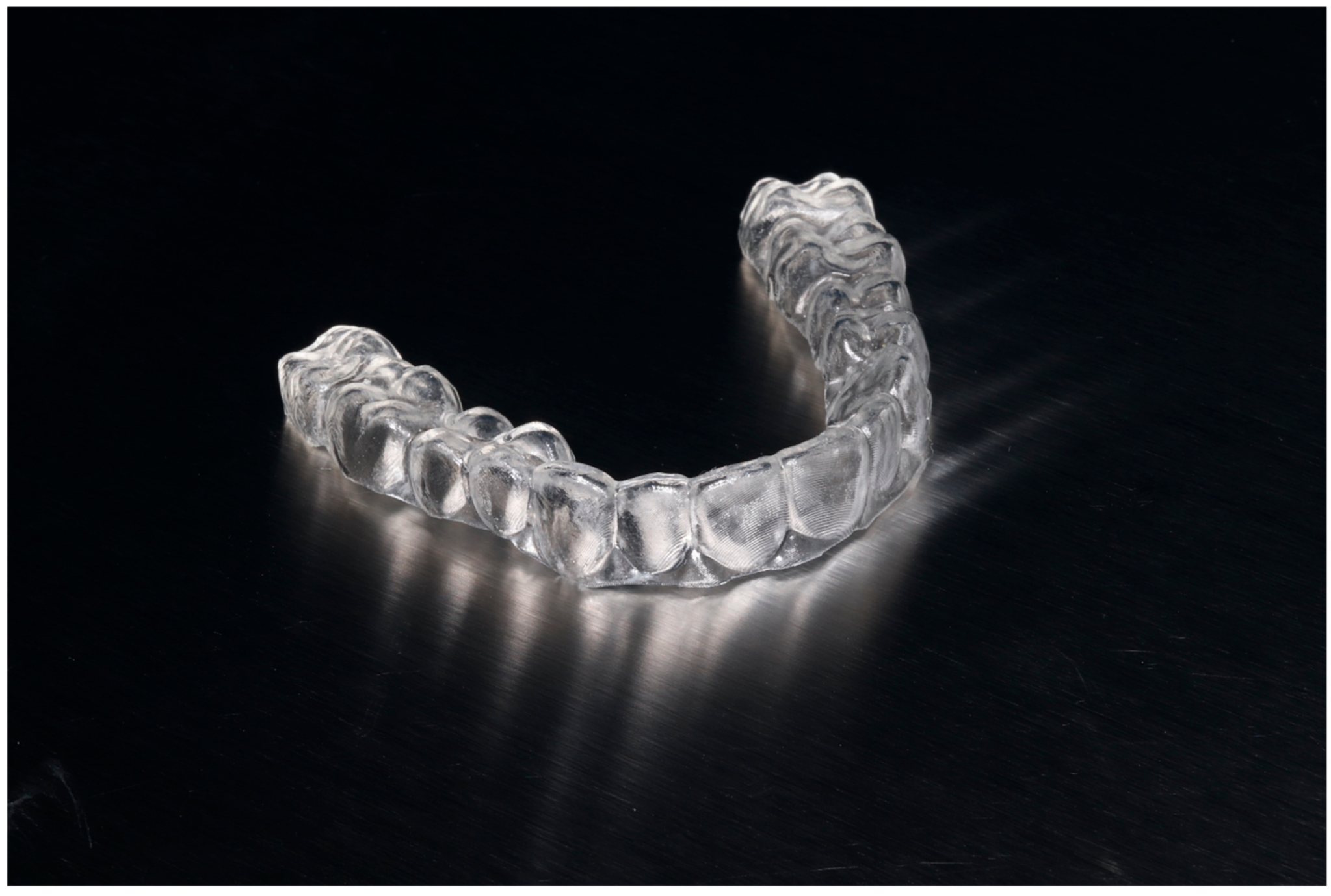 A single clear aligner on a dark reflective surface.